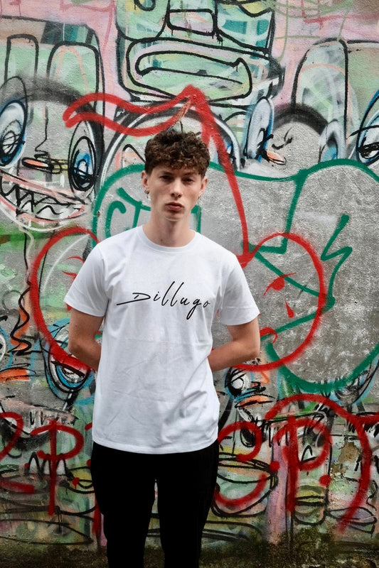 Male model wearing white t-shirt with "Dillugo" written across it (in black) on a graffiti backdrop.